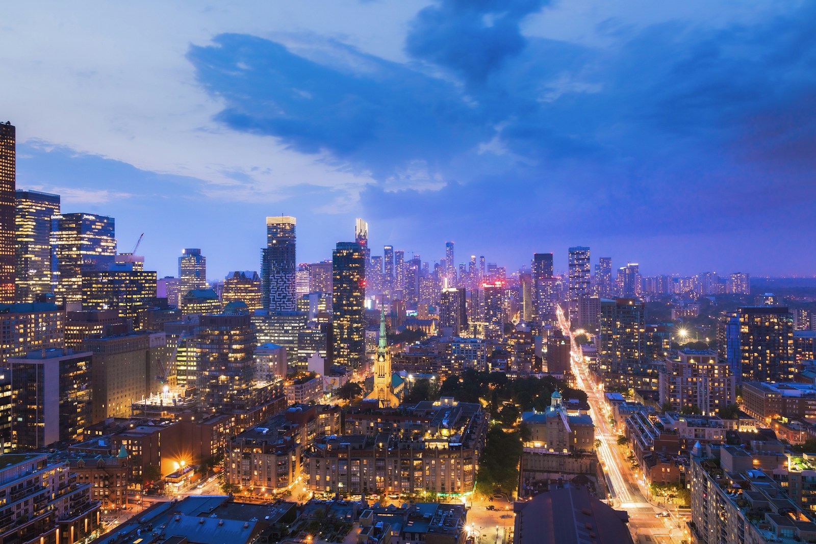 Illuminated city towers beneath a deep blue evening sky